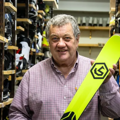 Établi d'atelier de ski vintage dans le Jura bernois, outils de précision et faisceau de lumière symbolisant la transmission du savoir technique.